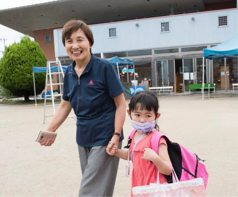 園庭で園児と手をつなぐ元園長先生